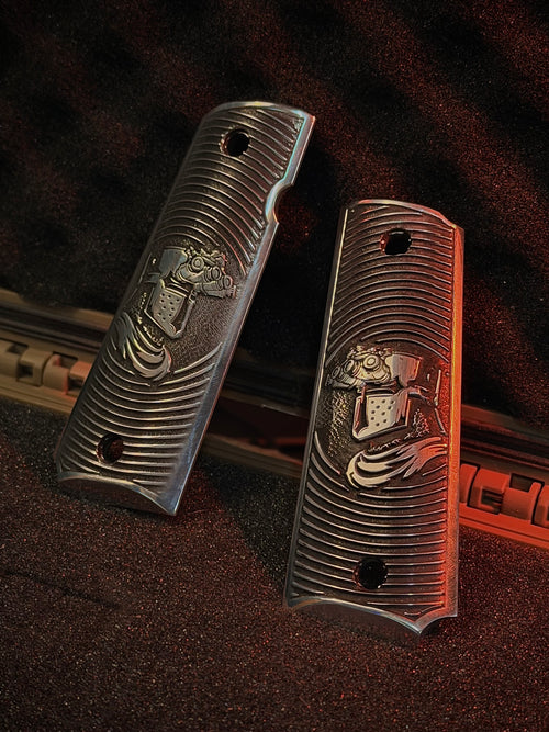 Two aluminum 1911 gun grips with engraved crusader designs on a textured surface.