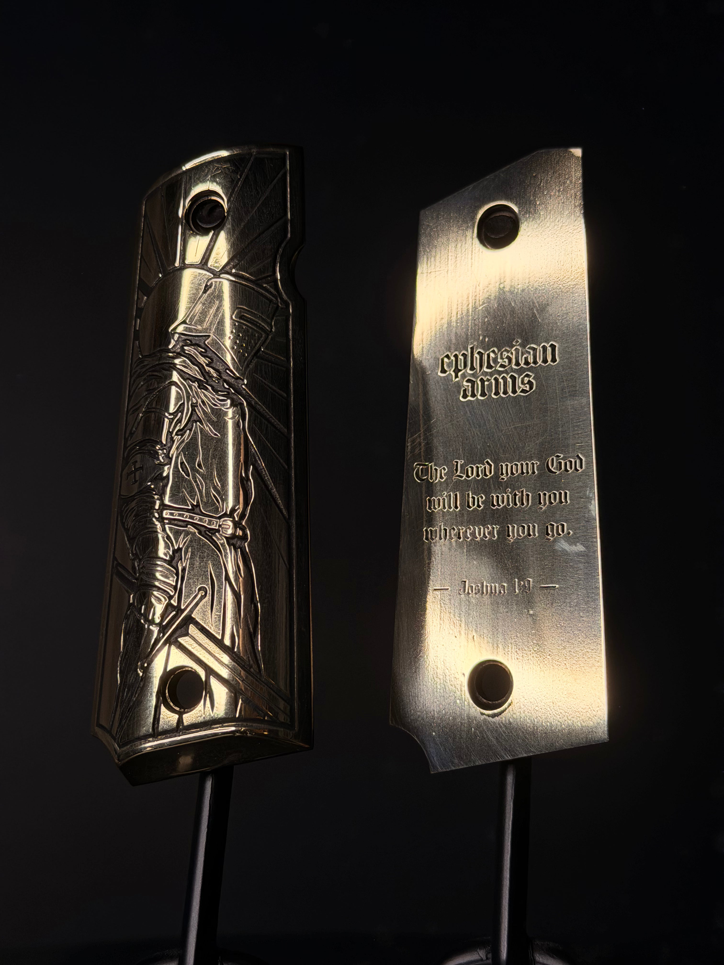 Two metallic gun grips with engraved designs on a black background